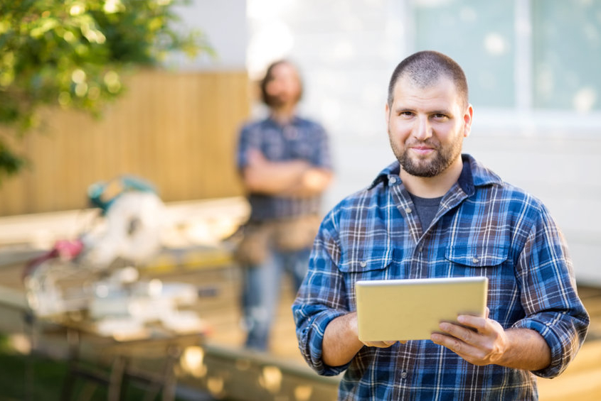 Man Holding Digital Tablet With Coworker Standing In Back